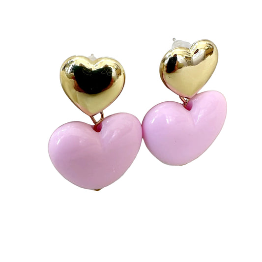 Heart-shaped earrings with gold top and pink bottom on a white stand.